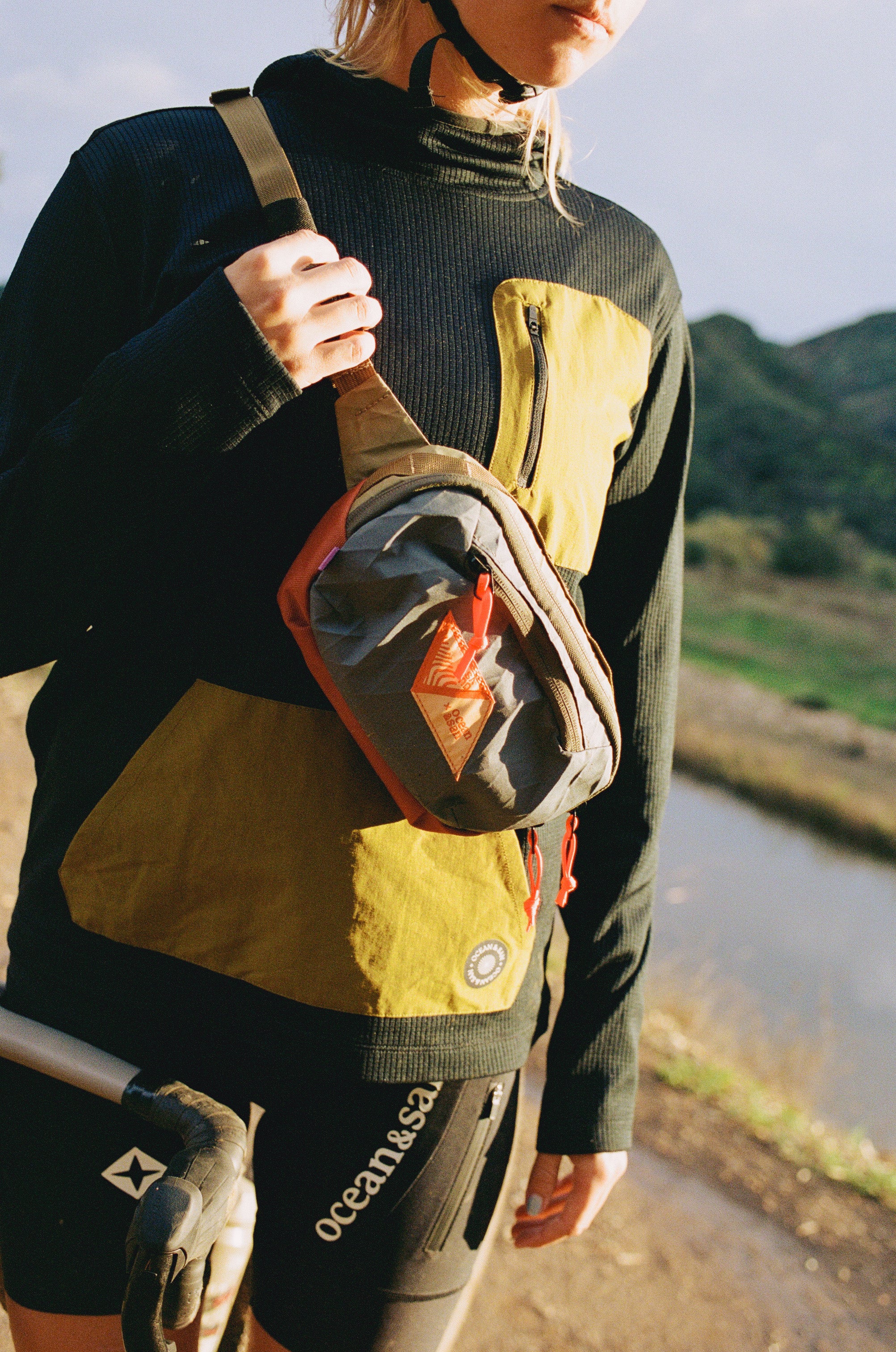 Person holding a crossbody sling bag with a scenic background